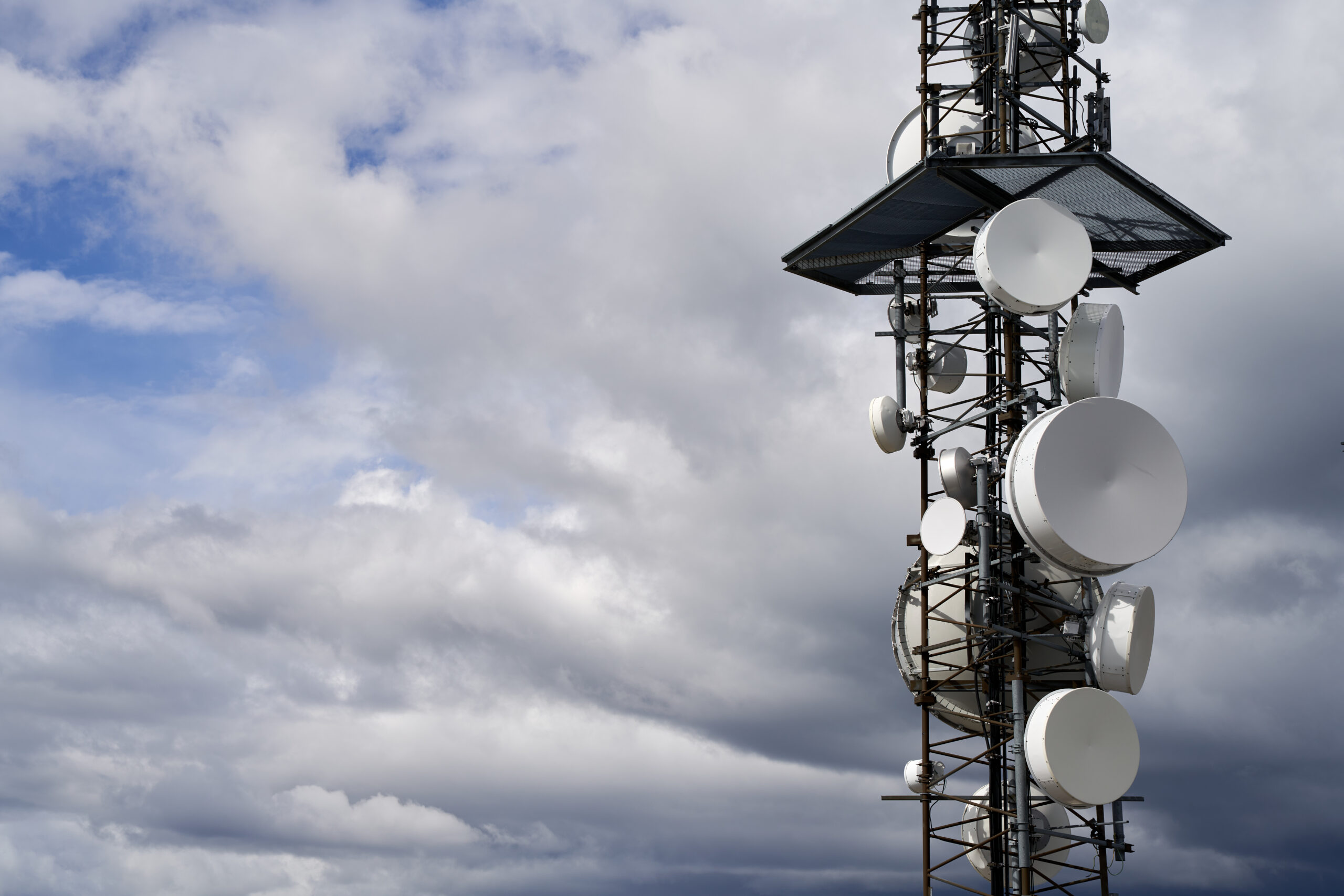 Telecommunications towers against cloudy sky background